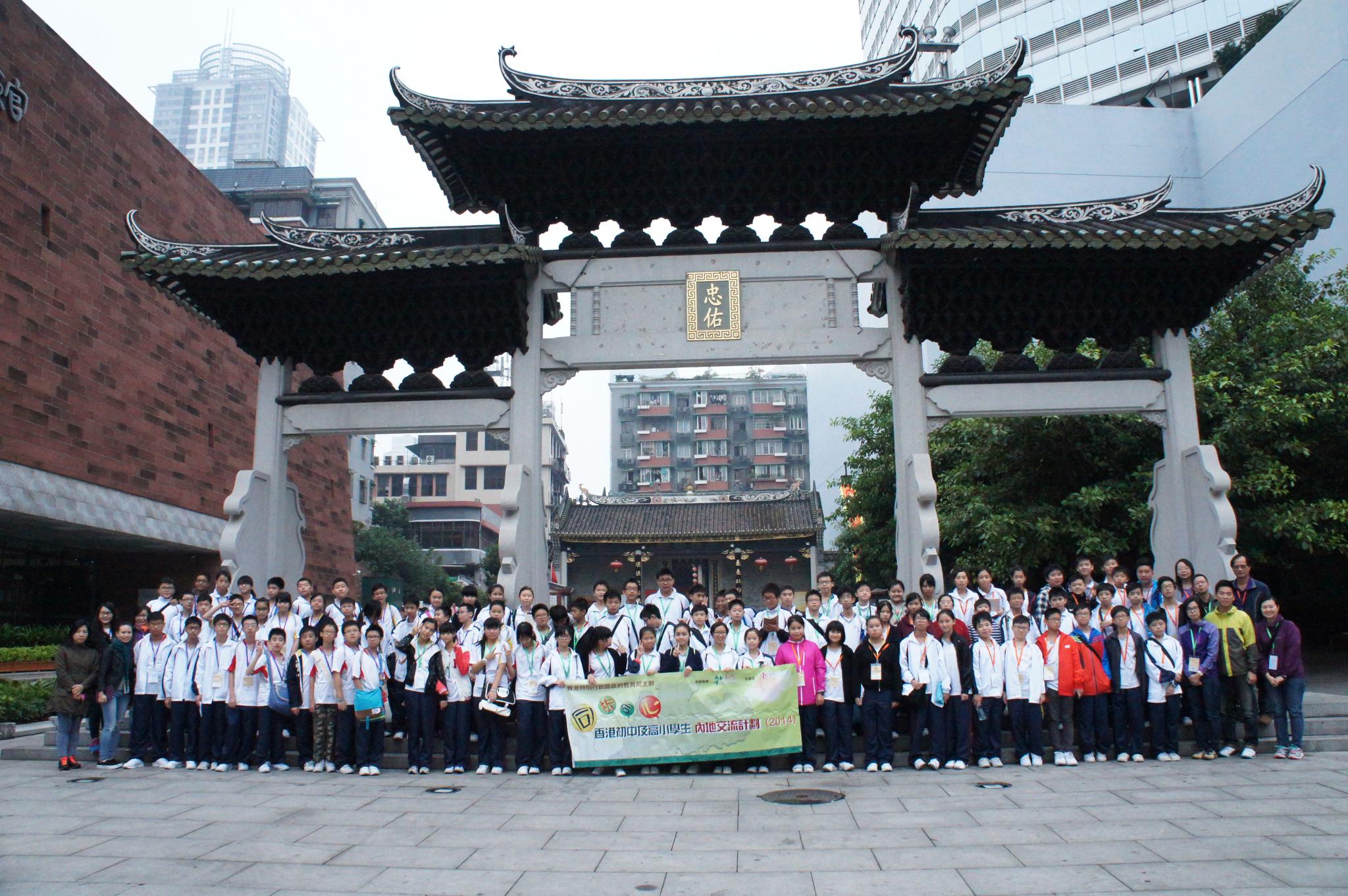 The students, teachers and tour guides are posing for a group photo together.